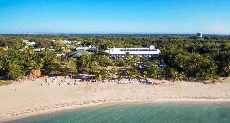 Aerial view of resort along a sandy beach surrounded by greenery.