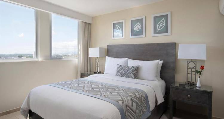 A hotel room with a double bed and minimalist decor.