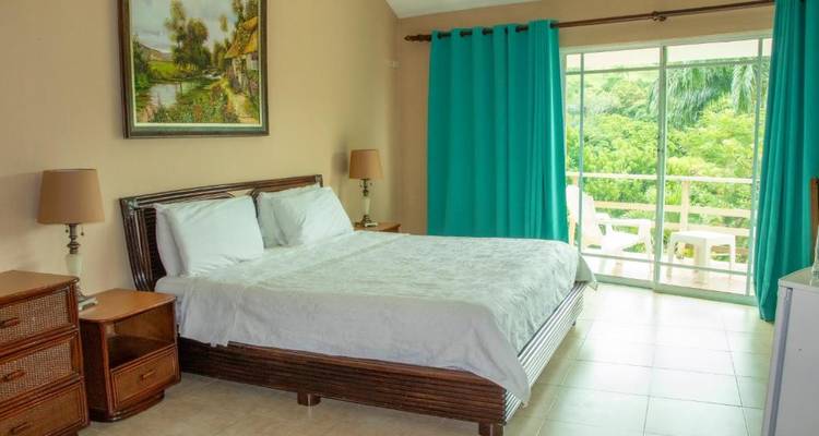 A hotel room with a wooden bed frame and a balcony view.