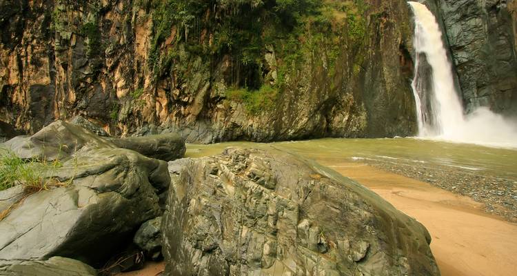 Une cascade qui dégringole le long d'une falaise rocheuse dans un bassin en contrebas.
