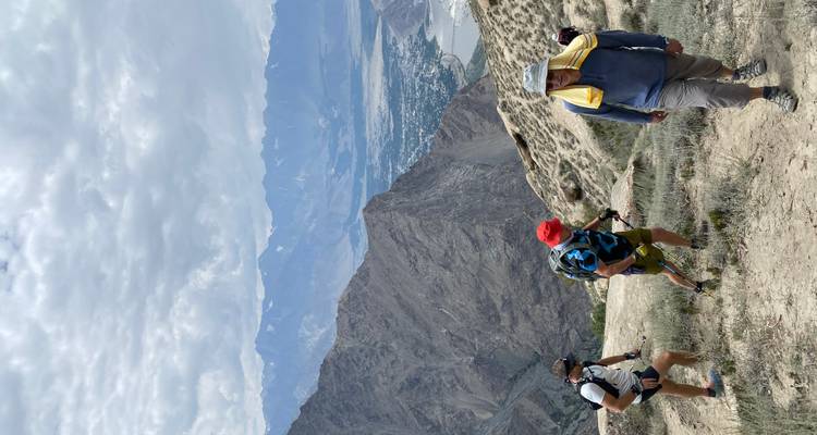 Senderistas caminando por un sendero de montaña con valles detrás de ellos.