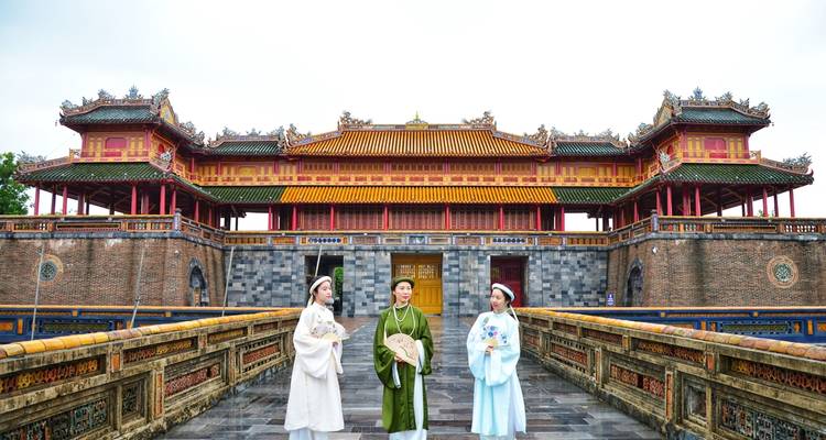 Trois personnes en tenue traditionnelle sur un site historique.
