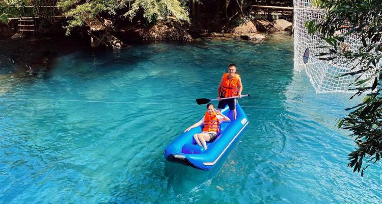 Deux personnes dans un bateau pneumatique bleu sur une eau claire.