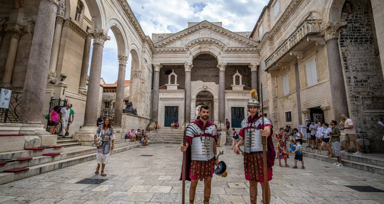 Des personnes en costumes romains dans une cour historique