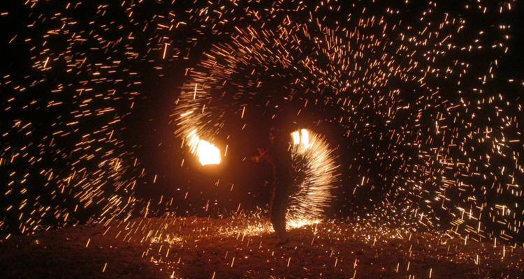 A fire performer creating spirals of sparks in the dark.