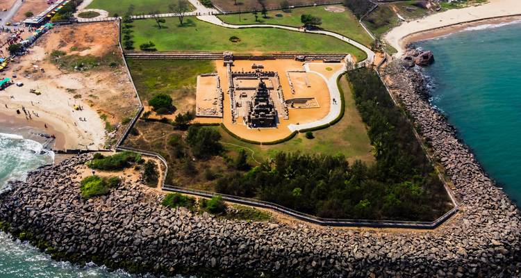 Vista aérea de un templo costero rodeado por una barrera rocosa.