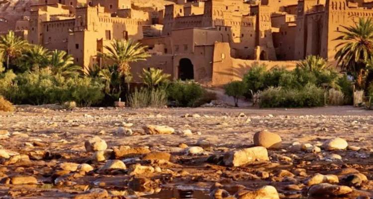 Pueblo fortificado antiguo de Ait Benhaddou con palmeras en primer plano.
