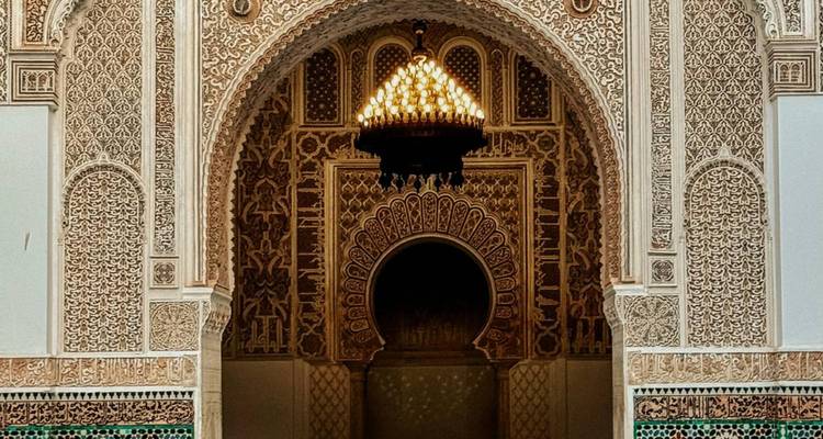 Entrada arqueada intrincada con candelabro dentro de un edificio marroquí.