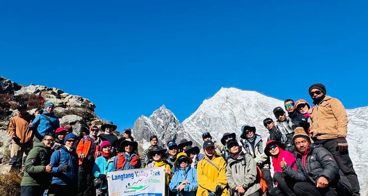 Groupe de randonneurs posant avec les montagnes de la vallée de Langtang en arrière-plan.
