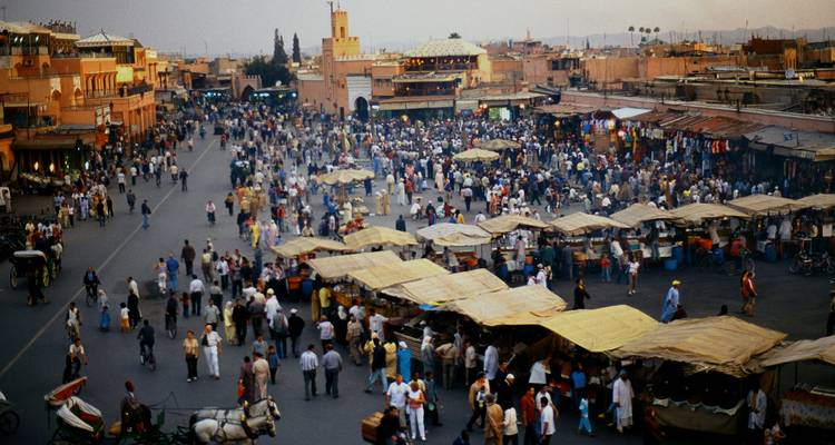 Une grande place publique grouillante d'activité, entourée de bâtiments historiques.