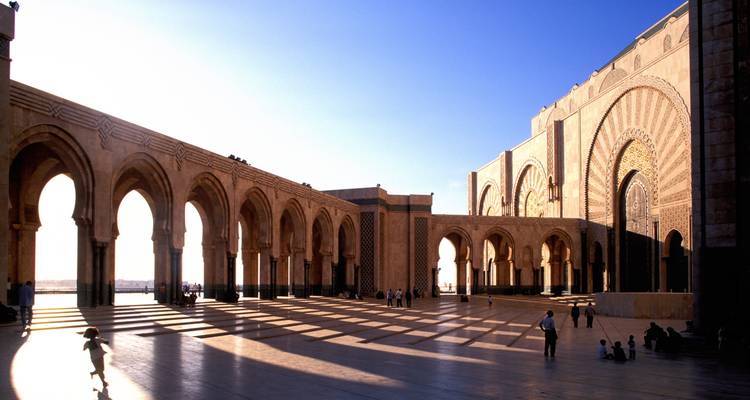 Une grande cour de mosquée avec des arches et des motifs d'ombre.