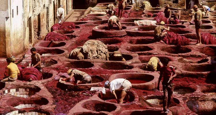 Des personnes travaillant dans une tannerie traditionnelle avec des cuves de teinture aux couleurs vives.