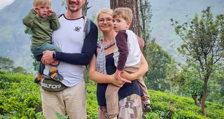 A family with two children posing in a green landscape.