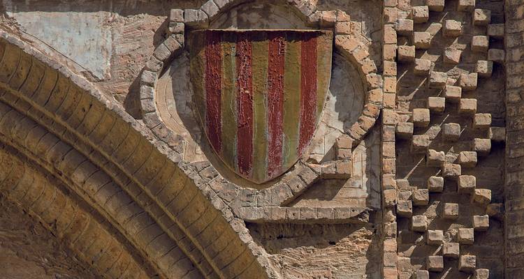 Escudo histórico en una pared de piedra desgastada.