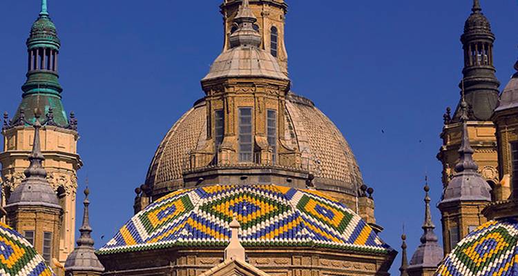 Cúpulas coloridas de la Basílica del Pilar en Zaragoza con un cielo azul despejado.