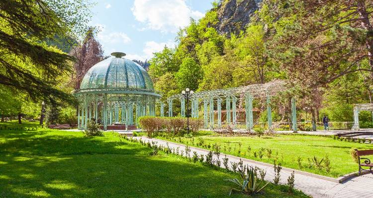 A glass pavilion in a garden setting.