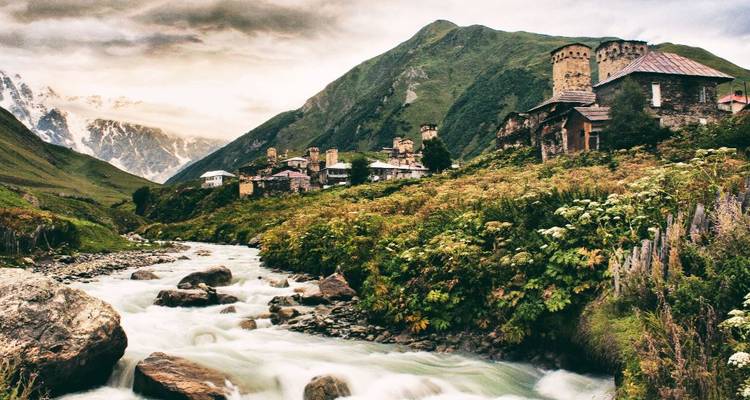 A river flowing through a lush green valley with stone towers.