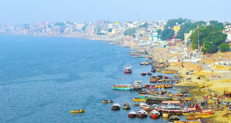 Des bateaux flottant le long d'une berge animée avec un paysage urbain en arrière-plan.