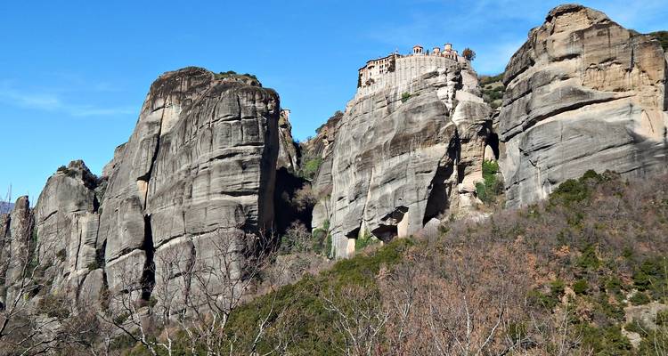 Imposantes falaises de grès des Météores avec un monastère perché en hauteur contre le ciel bleu.