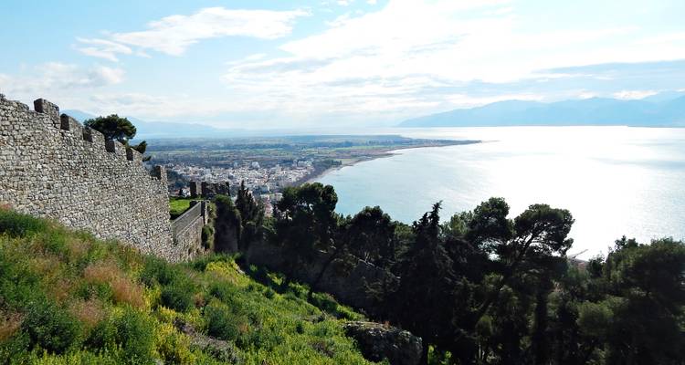 Ville côtière et golfe scintillant vus depuis les remparts verdoyants du château.