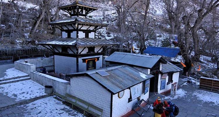Un pequeño templo rodeado de nieve, con gente alrededor.