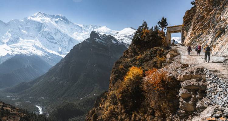 Sentier de randonnée au Népal avec des randonneurs et l'Himalaya au loin.