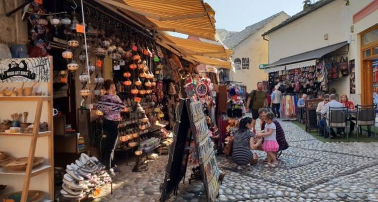 Mercado al aire libre con varios productos y gente paseando.