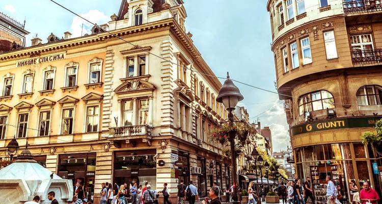 Straatscène met historische gebouwen en wandelende mensen.