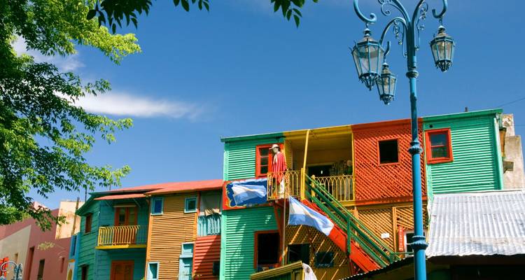 Maisons en tôle ondulée aux couleurs vives dans le quartier de La Boca avec des drapeaux argentins flottant contre un ciel bleu éclatant