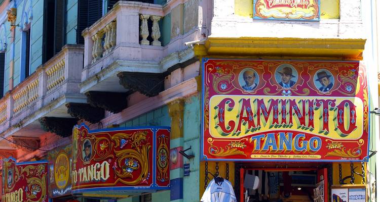Enseigne de vitrine aux couleurs vives indiquant 'Caminito Tango' avec des motifs folkloriques argentins colorés sur la façade d'un bâtiment historique