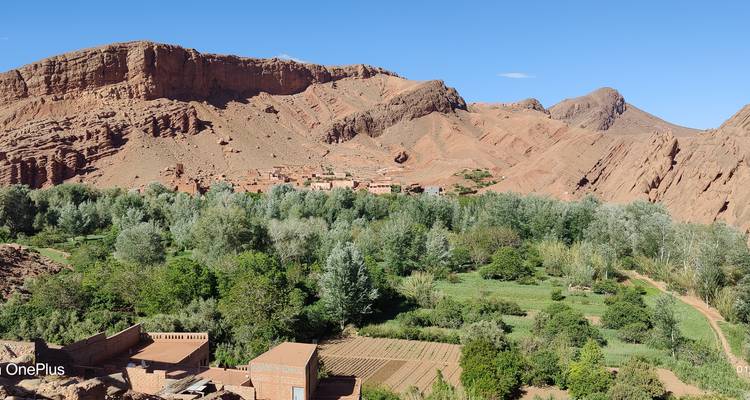 Une vallée luxuriante avec un village et des montagnes en arrière-plan.