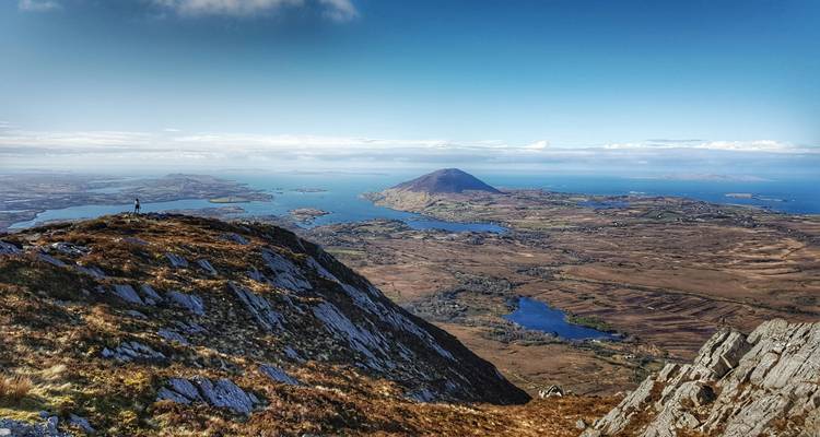 Vista panorámica desde una montaña con una amplia extensión de tierra y agua.