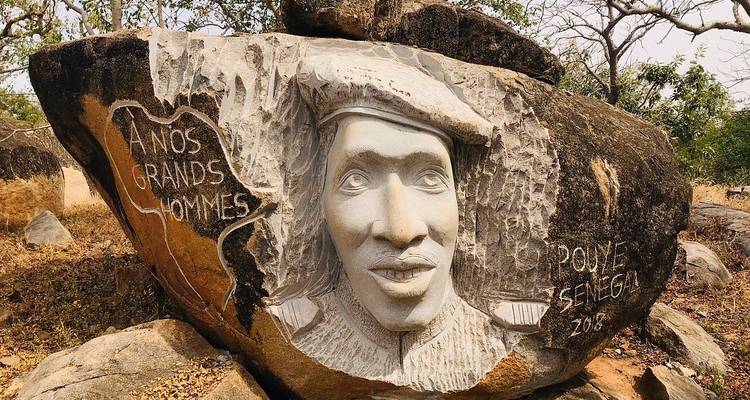 Sculpture en pierre d'un visage dans un cadre naturel.