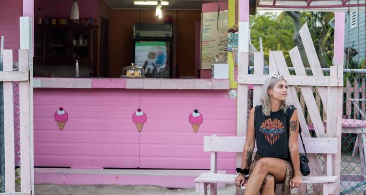 Une femme assise devant un magasin rose vif.