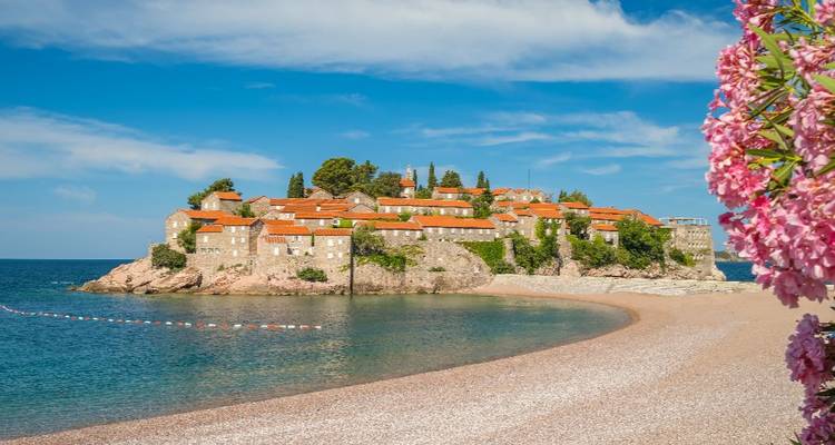 Coastal village with red-roofed buildings and clear water.