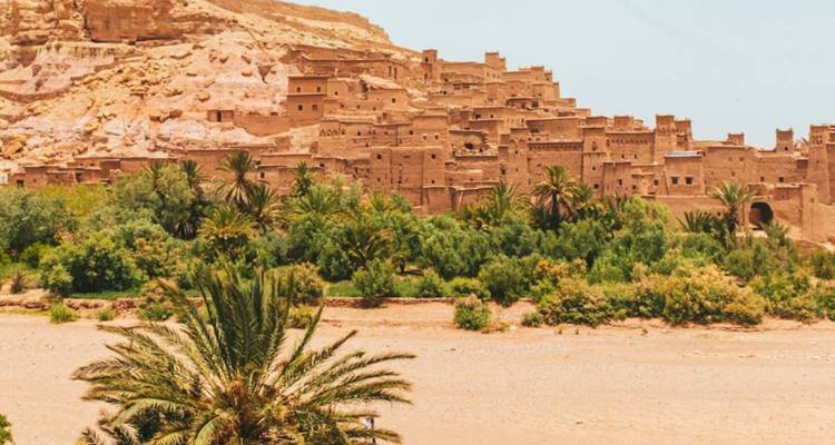 Uitzicht op het oude Ait Benhaddou met palmbomen.