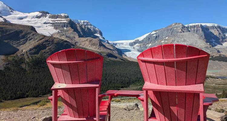 Dos sillas rojas frente a una cordillera cubierta de nieve.