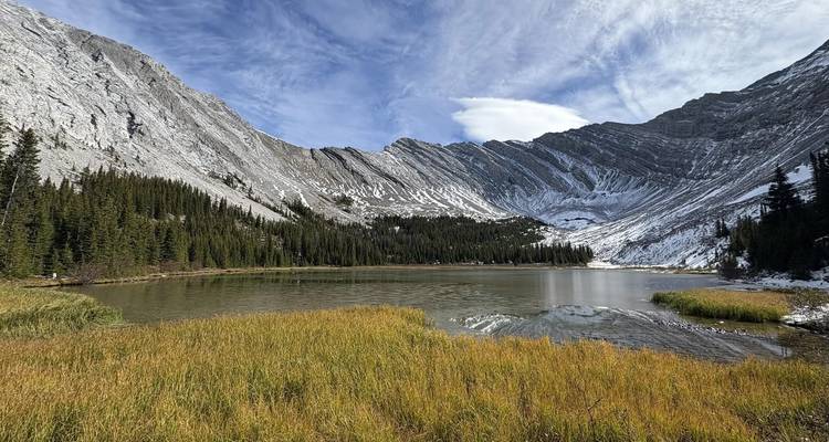 Paisaje de montaña con un lago rodeado de campos de hierba.