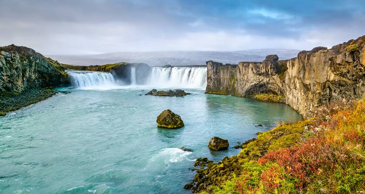 Godafoss-Wasserfall mit blauem Wasser und üppiger Umgebung.
