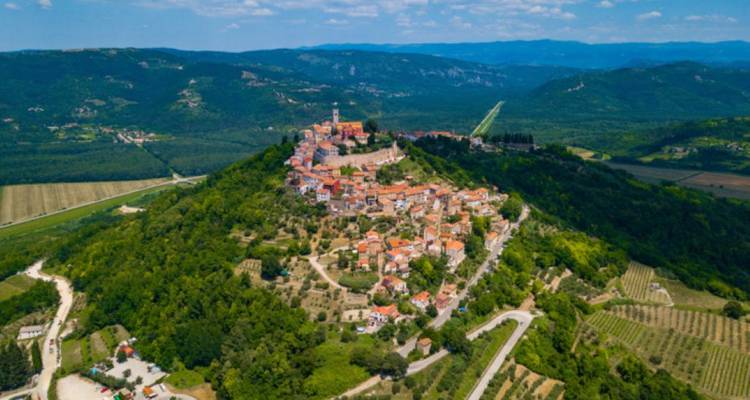 Vista aérea de un pueblo en la cima de una colina y el paisaje circundante.