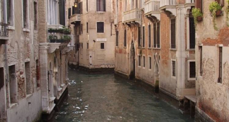 Canal estrecho entre edificios antiguos en Venecia.