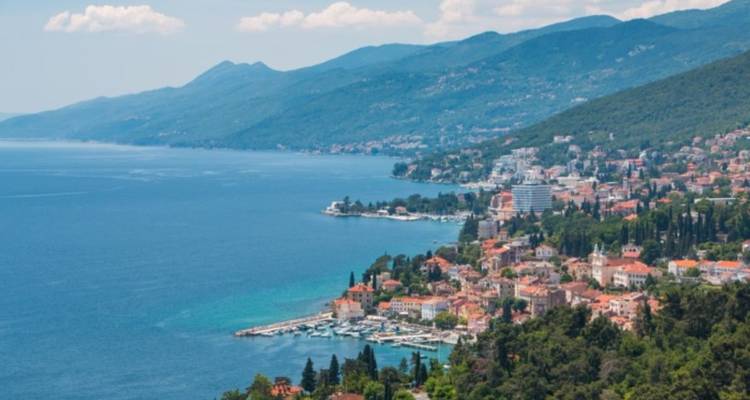 Vista panorámica de un pueblo costero frente al océano y las montañas.