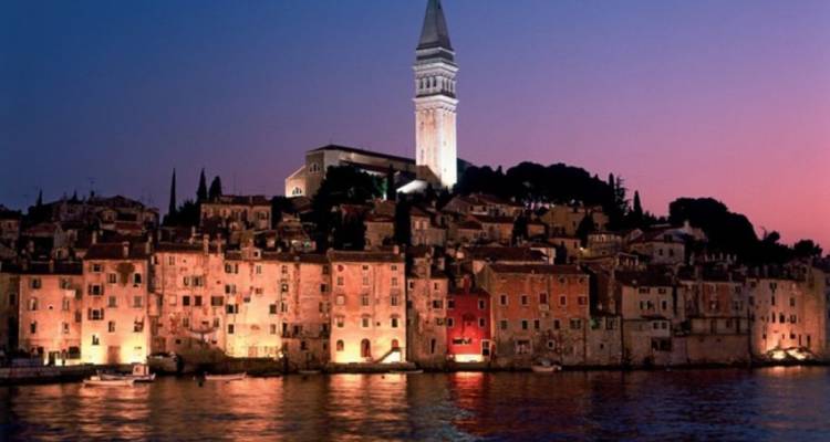 Vista nocturna de Rovinj con edificios iluminados.