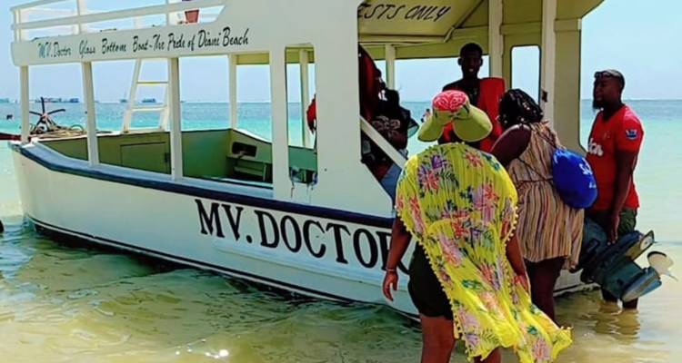 Des gens embarquant sur un bateau nommé MV Doctor sur une plage.