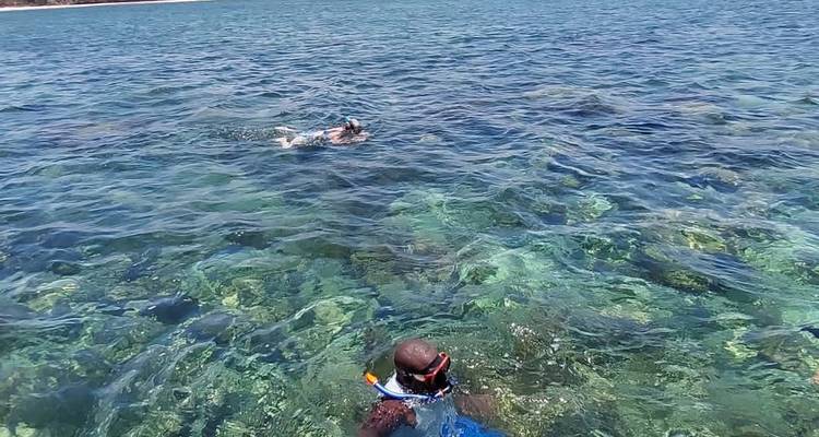 Deux personnes faisant de la plongée avec tuba dans une eau bleue claire avec des récifs visibles.