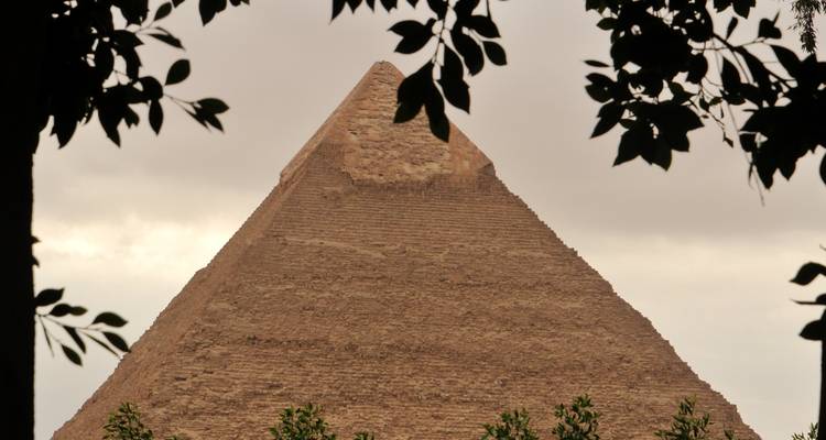 Pyramide partiellement obscurcie par les arbres au premier plan.