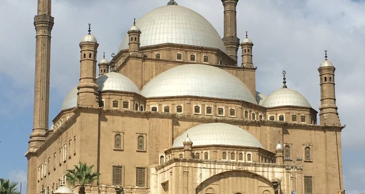 Grande mosquée avec plusieurs dômes et minarets sous un ciel dégagé.