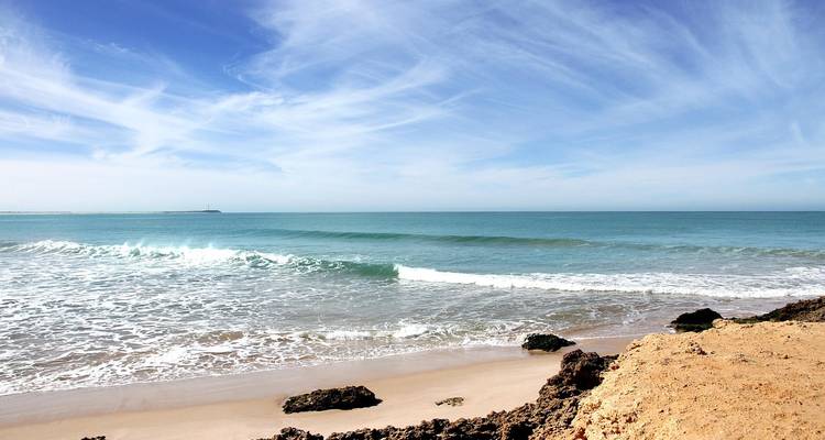 Vue côtière avec des vagues douces et un ciel bleu clair.