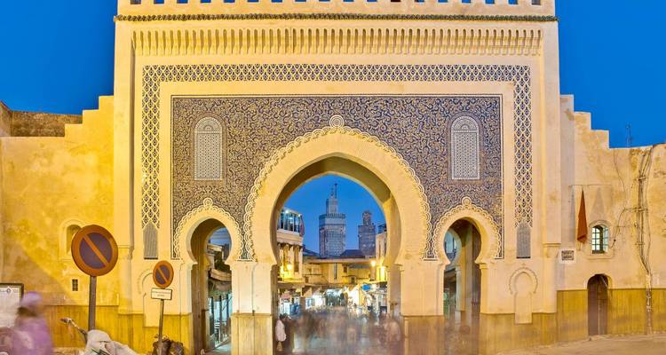 Portail bleu arqué avec des motifs complexes au coucher du soleil.