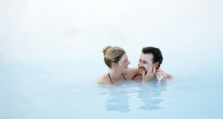 Pareja en una laguna azul con niebla y mascarillas faciales.